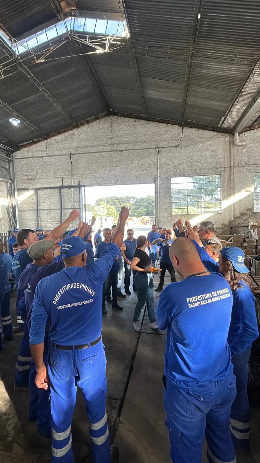 Equipe de obras públicas em roda de conversa num galpão